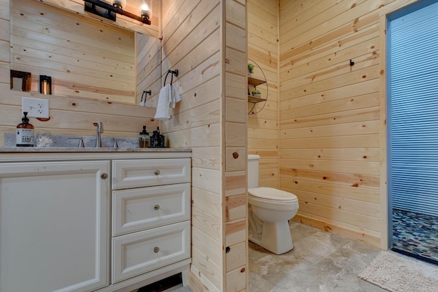 bathroom with vanity, toilet, and wooden walls