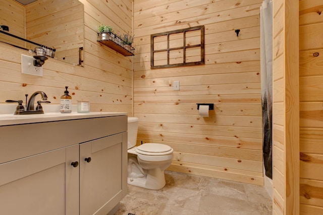 bathroom with vanity, wood walls, and toilet