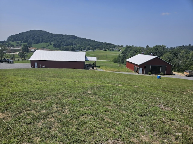 view of yard featuring a mountain view, a rural view, and an outdoor structure