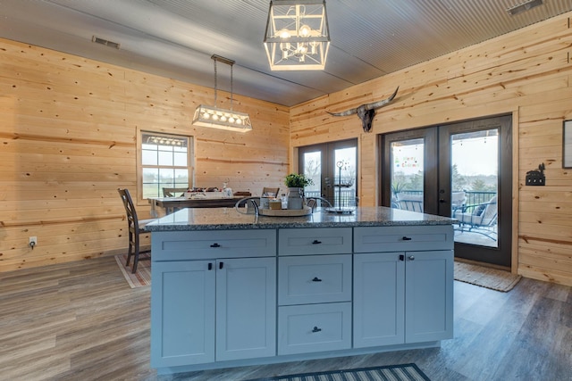 kitchen featuring french doors, wooden walls, plenty of natural light, and pendant lighting