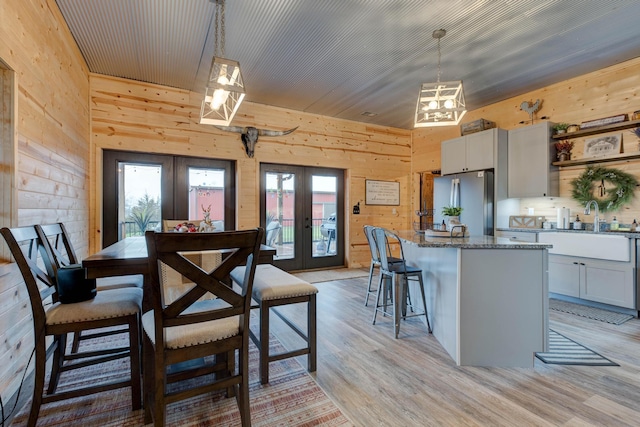 dining area featuring a healthy amount of sunlight, wooden walls, and french doors