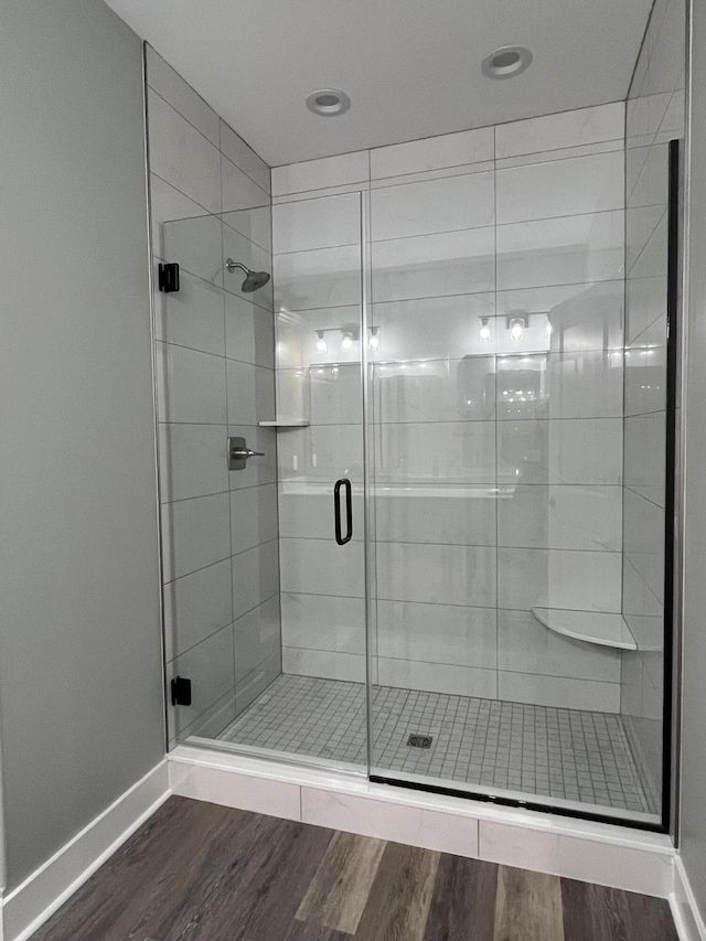 full bath with baseboards, wood finished floors, and a shower stall