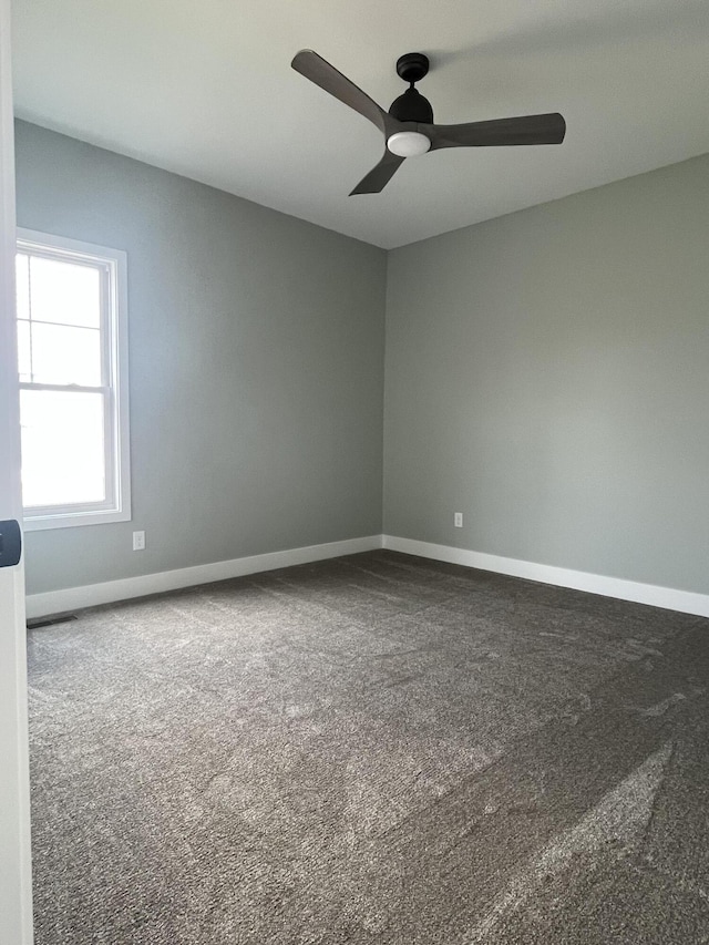 carpeted spare room with a ceiling fan and baseboards