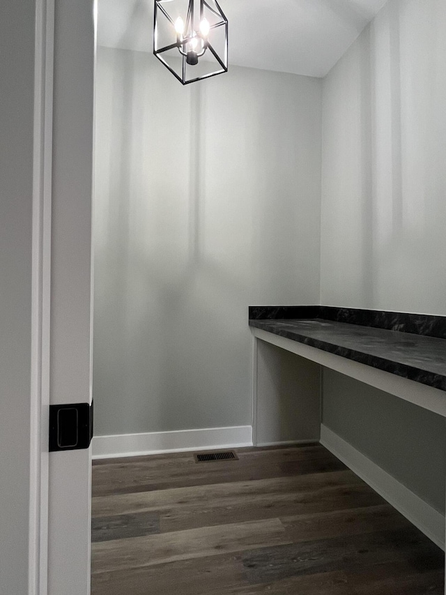 spacious closet with a chandelier, dark wood finished floors, and visible vents