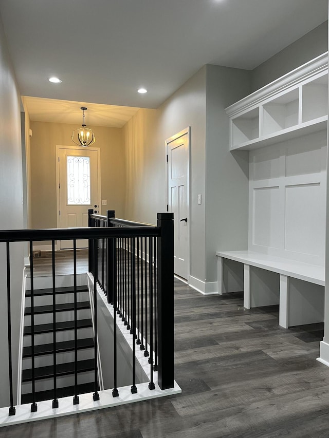 stairway with wood-type flooring and an inviting chandelier