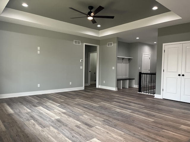 unfurnished living room featuring recessed lighting, a raised ceiling, visible vents, wood finished floors, and baseboards