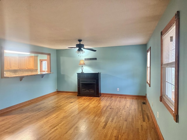 unfurnished living room with light wood-type flooring and ceiling fan