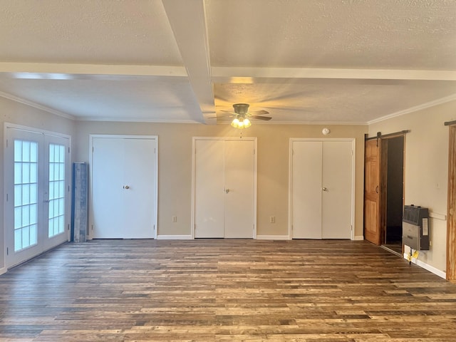 interior space featuring heating unit, dark wood-type flooring, a barn door, beamed ceiling, and multiple closets