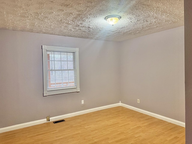 unfurnished room featuring hardwood / wood-style flooring and a textured ceiling