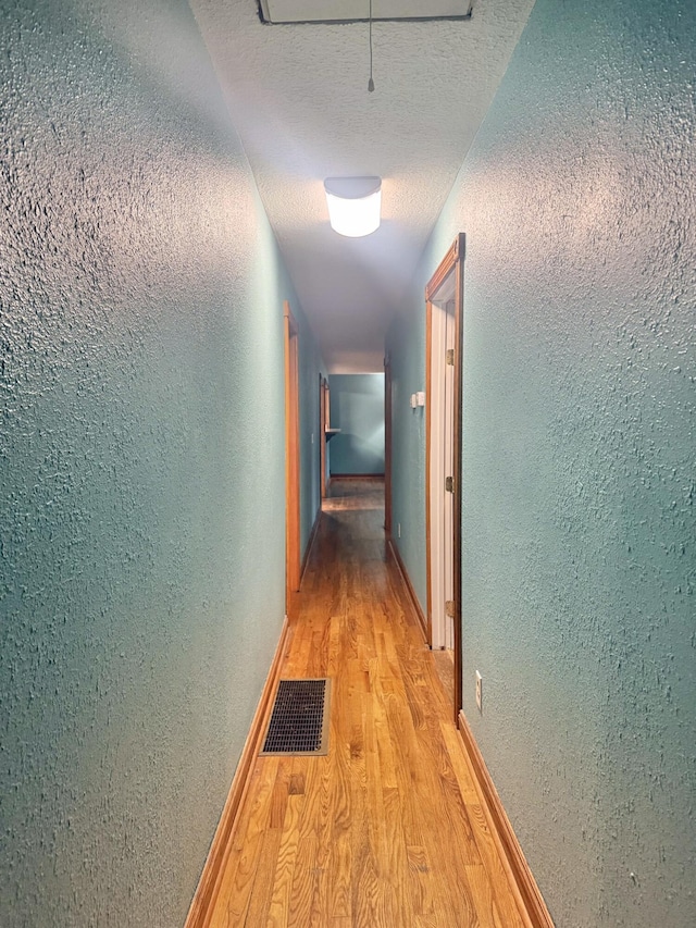 hall featuring a textured ceiling and light wood-type flooring