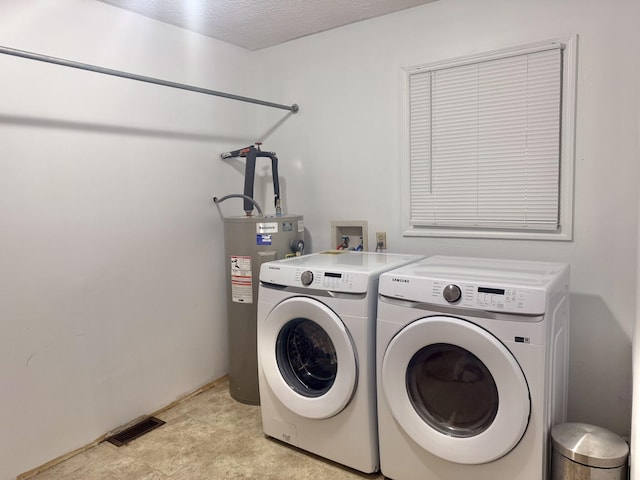 clothes washing area featuring washing machine and dryer, electric water heater, and a textured ceiling