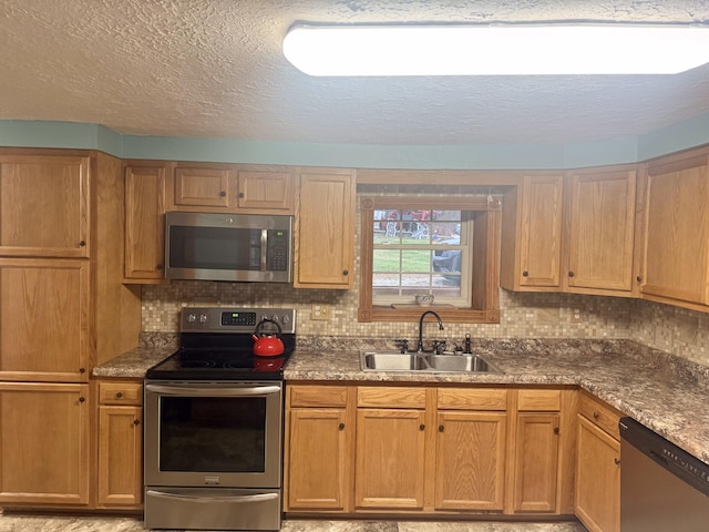 kitchen with a textured ceiling, sink, appliances with stainless steel finishes, and tasteful backsplash