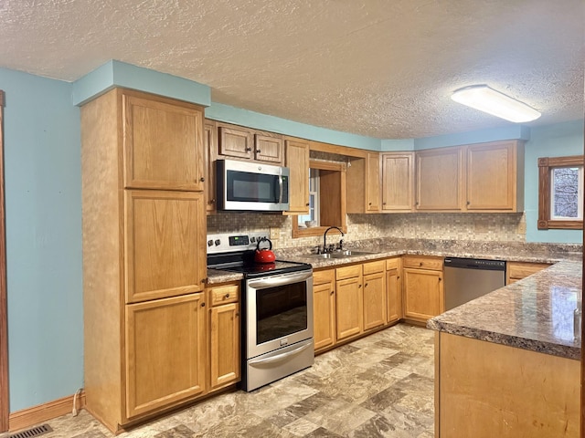 kitchen with tasteful backsplash, sink, a textured ceiling, and appliances with stainless steel finishes