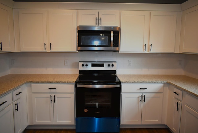 kitchen with light stone counters, white cabinetry, and appliances with stainless steel finishes