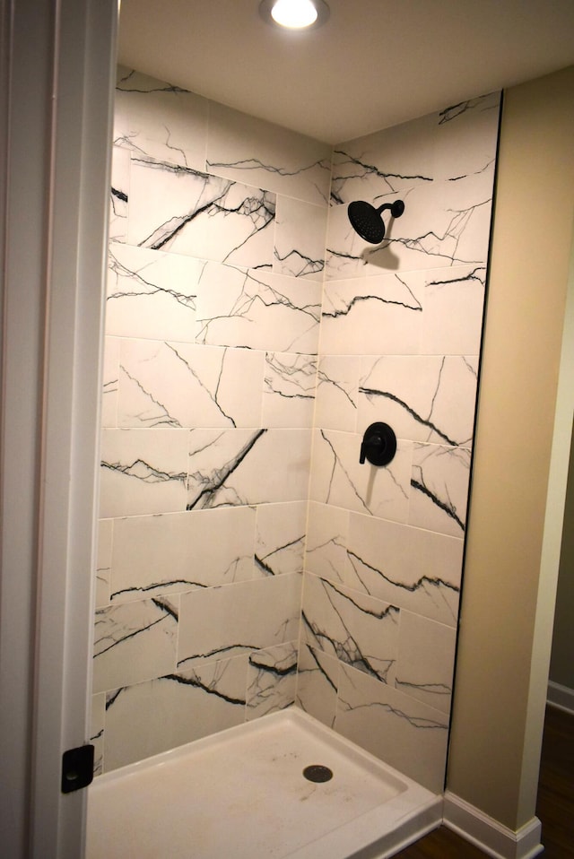 bathroom with hardwood / wood-style flooring and a tile shower