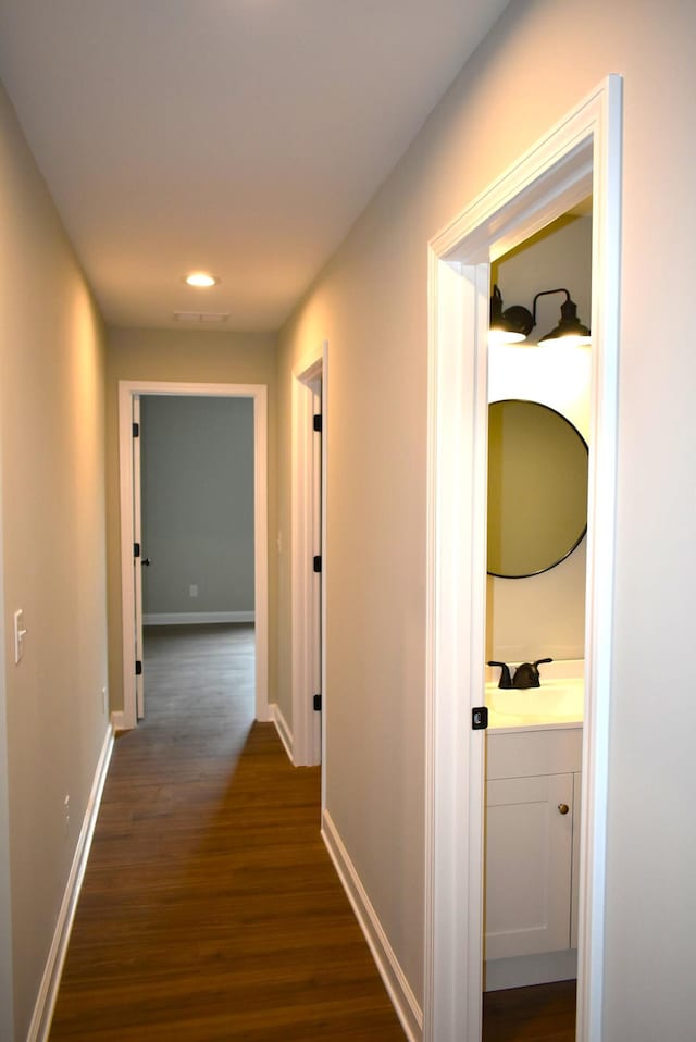 corridor with sink and dark wood-type flooring