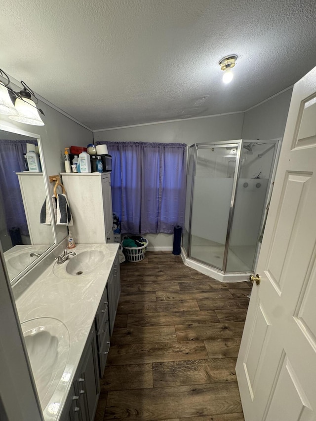 bathroom with hardwood / wood-style flooring, vanity, an enclosed shower, and a textured ceiling