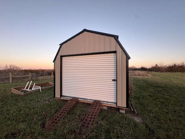 outdoor structure at dusk featuring a garage and a lawn