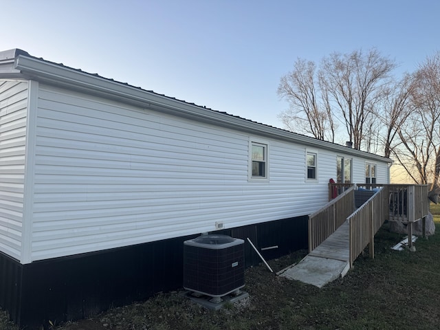 property exterior at dusk with cooling unit and a deck