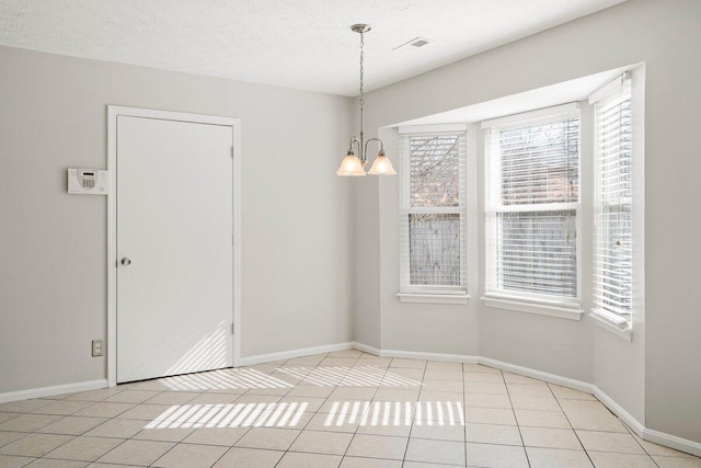 unfurnished dining area featuring tile patterned floors, visible vents, a textured ceiling, an inviting chandelier, and baseboards