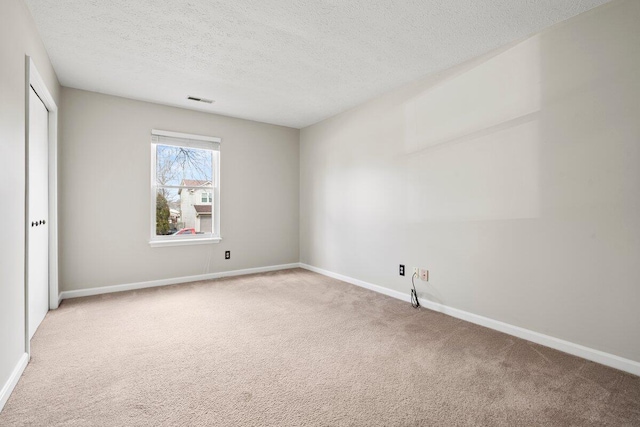 carpeted empty room with visible vents, a textured ceiling, and baseboards