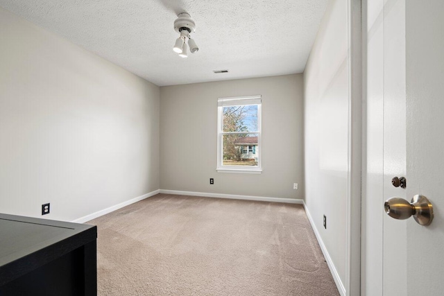 spare room with visible vents, baseboards, light colored carpet, and a textured ceiling