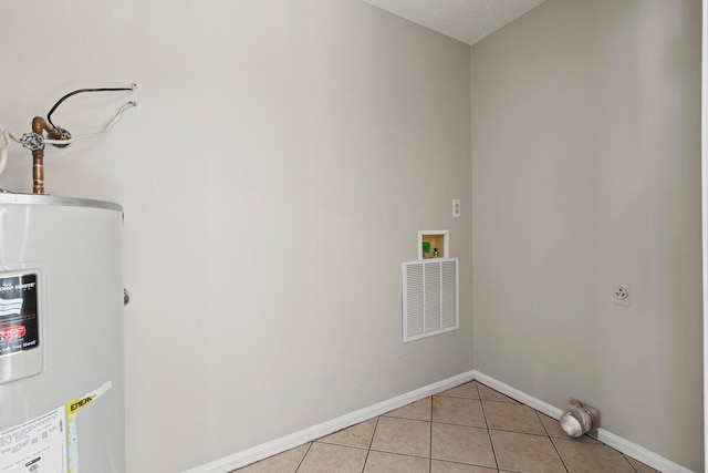 laundry area with visible vents, baseboards, water heater, laundry area, and light tile patterned floors