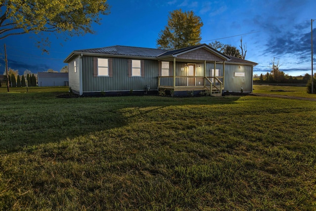 back house at dusk with a yard and a porch