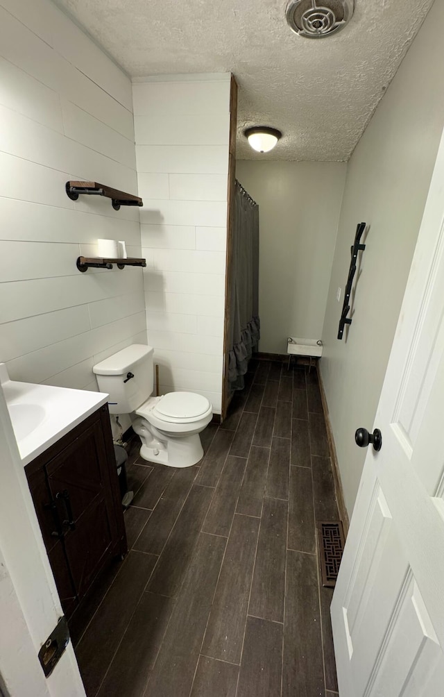 bathroom featuring a shower with curtain, vanity, a textured ceiling, and toilet