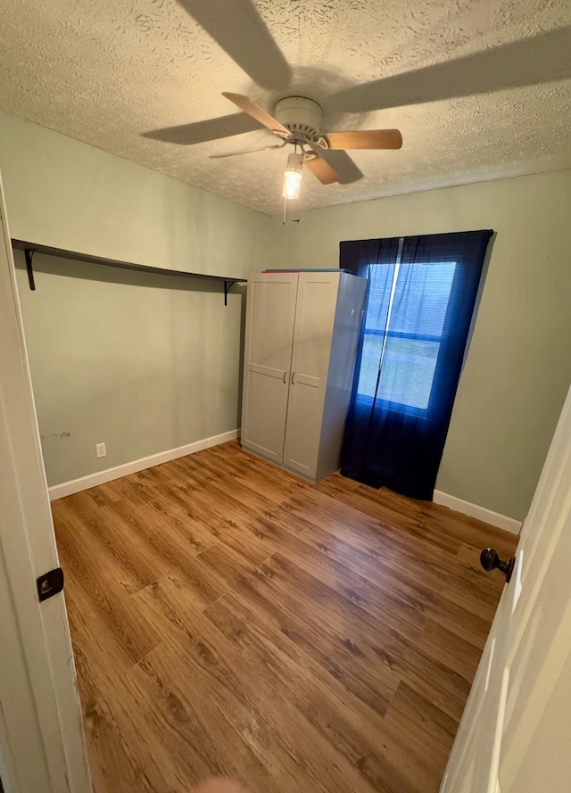 unfurnished bedroom with ceiling fan, a textured ceiling, and light wood-type flooring