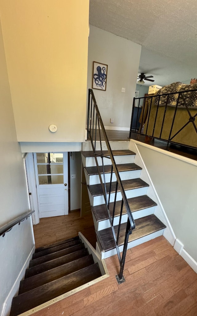 stairway with hardwood / wood-style flooring, ceiling fan, and a textured ceiling