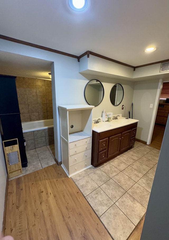 bathroom with vanity, wood-type flooring, crown molding, and a tub