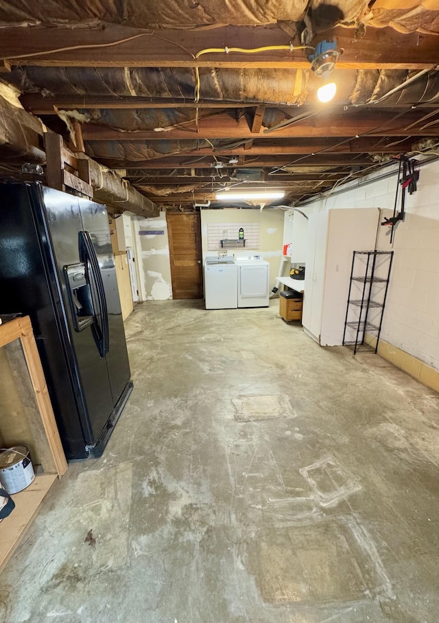 basement featuring washer and dryer and black fridge with ice dispenser