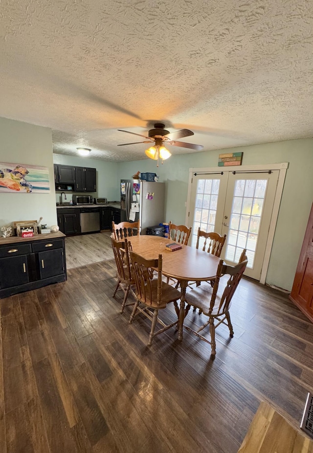 dining room with dark wood-type flooring, french doors, sink, ceiling fan, and a textured ceiling