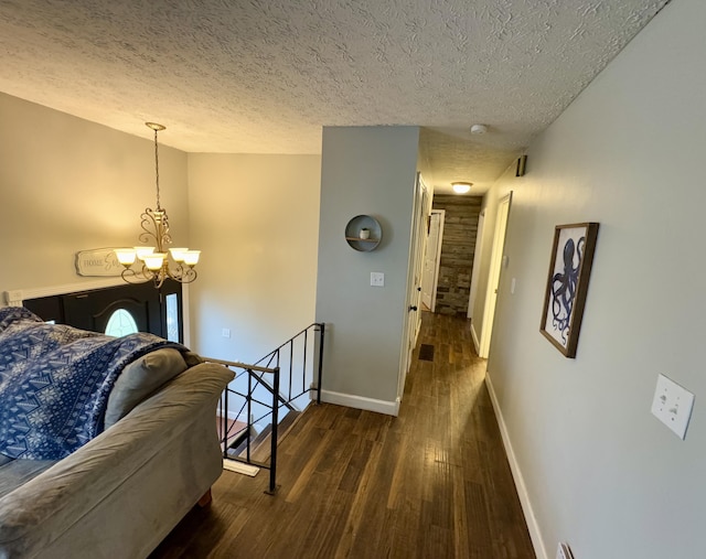 corridor featuring a notable chandelier, dark hardwood / wood-style floors, and a textured ceiling