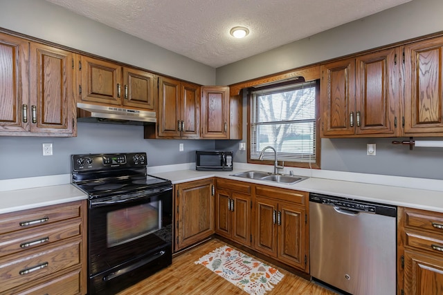 kitchen with black appliances, light hardwood / wood-style floors, sink, and a textured ceiling