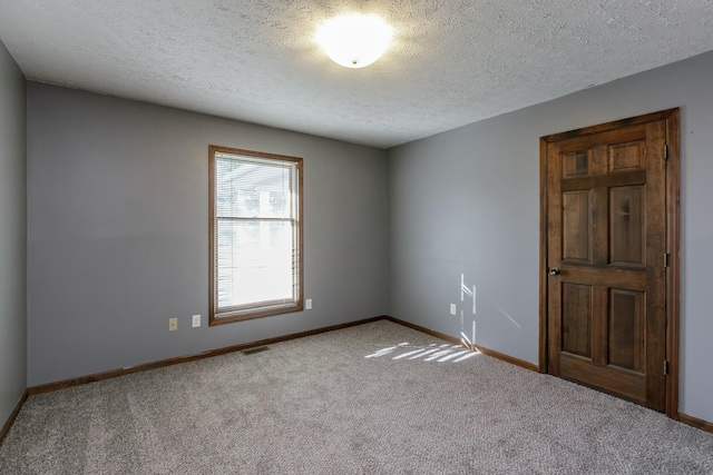 spare room featuring light colored carpet and a textured ceiling