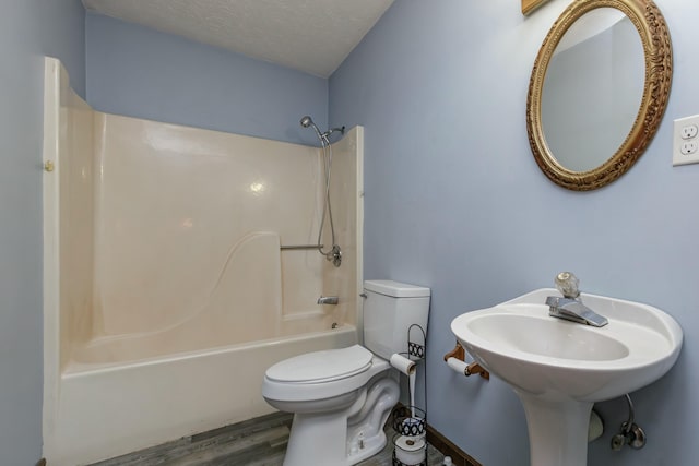 bathroom with shower / bathing tub combination, wood-type flooring, a textured ceiling, and toilet