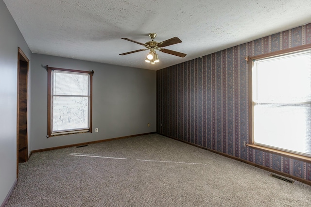 empty room with carpet flooring, a textured ceiling, and ceiling fan