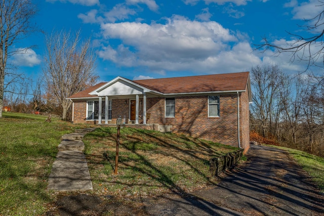 ranch-style home featuring covered porch and a front yard