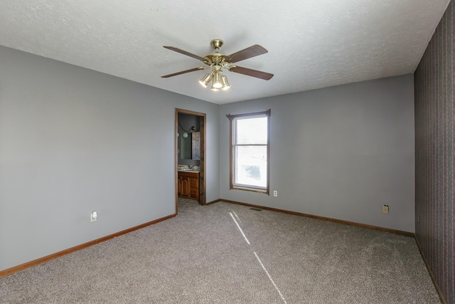 empty room featuring ceiling fan, a textured ceiling, and light carpet