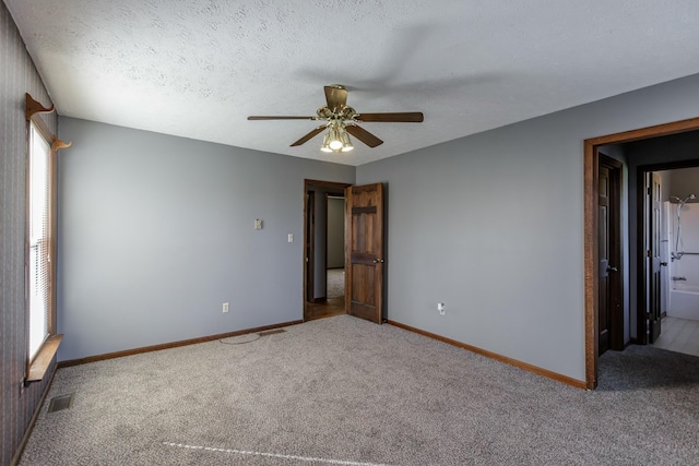 carpeted spare room featuring ceiling fan and a textured ceiling