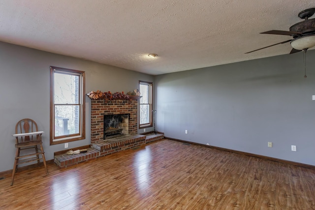 unfurnished living room featuring hardwood / wood-style floors, plenty of natural light, a fireplace, and a textured ceiling