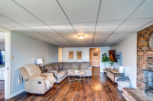 living room featuring radiator heating unit, a brick fireplace, and dark hardwood / wood-style flooring