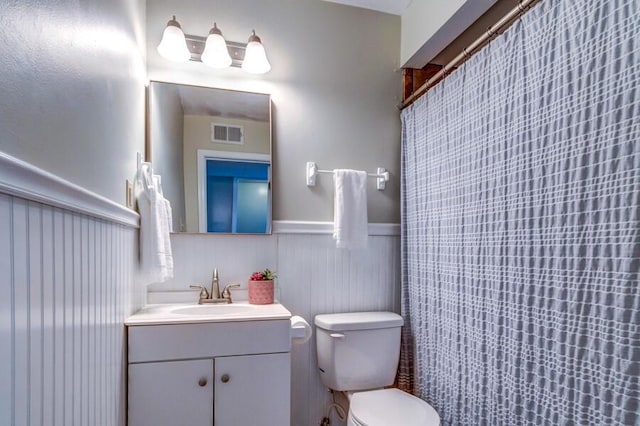 bathroom featuring toilet, vanity, and walk in shower