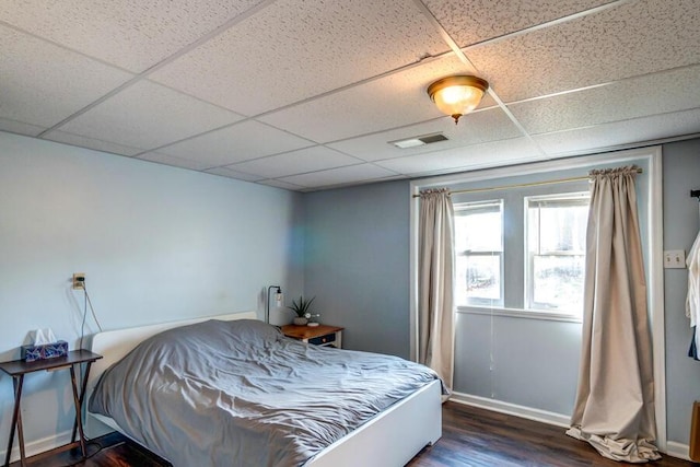 bedroom with a drop ceiling and dark hardwood / wood-style flooring