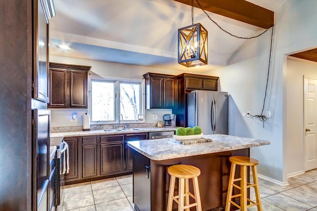 kitchen with a center island, hanging light fixtures, a kitchen breakfast bar, sink, and stainless steel appliances