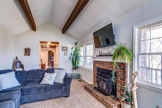 living room featuring a healthy amount of sunlight, carpet floors, vaulted ceiling with beams, and a wood stove