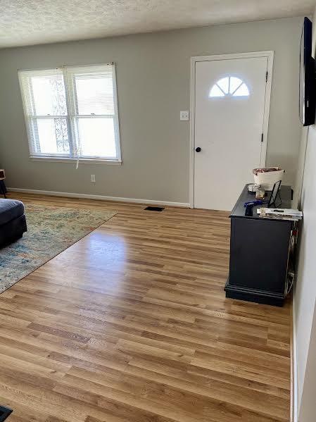 foyer entrance with a textured ceiling and light hardwood / wood-style flooring