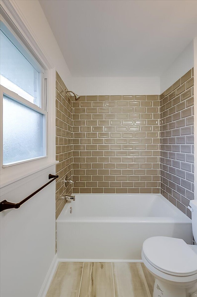 bathroom with toilet and tiled shower / bath